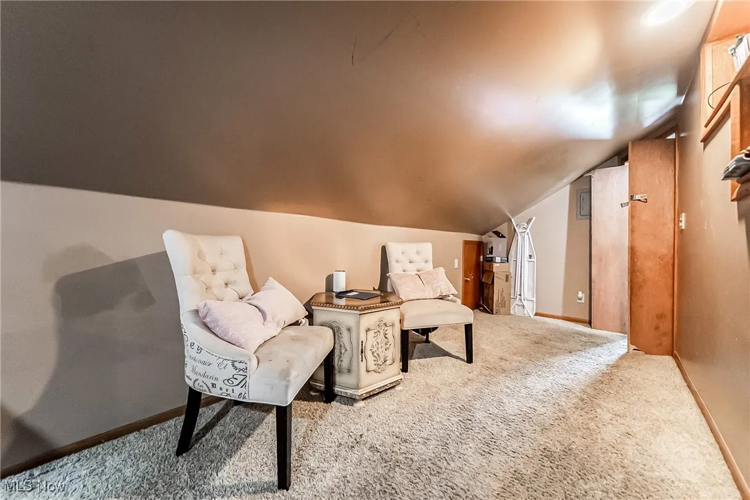 Sitting room with carpet flooring and vaulted ceiling in the primary bedroom