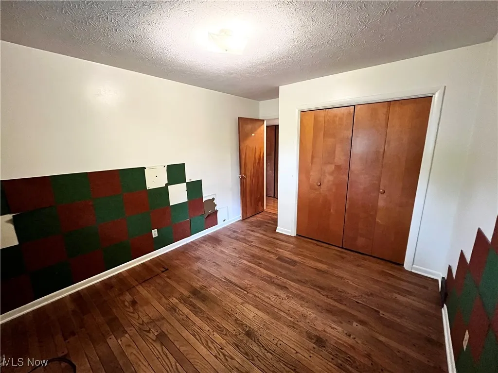 Unfurnished bedroom with hardwood / wood-style floors, a textured ceiling, and a closet