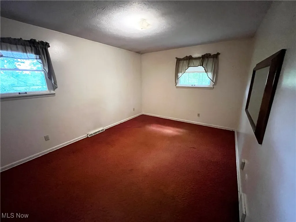 Unfurnished room with a textured ceiling and carpet floors