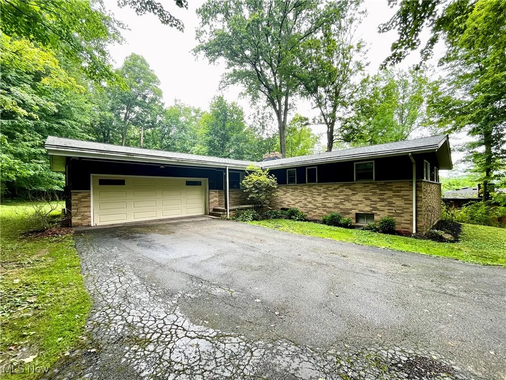 Ranch-style home featuring asphalt driveway, a garage, and stone siding