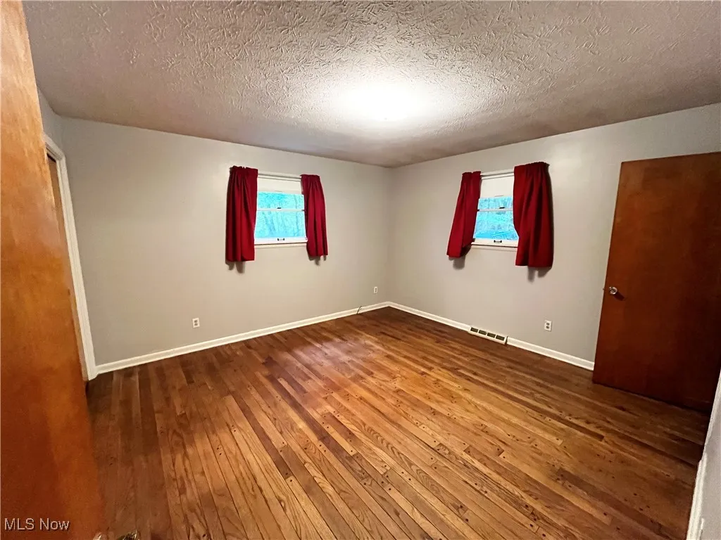 Unfurnished bedroom with hardwood / wood-style flooring and a textured ceiling