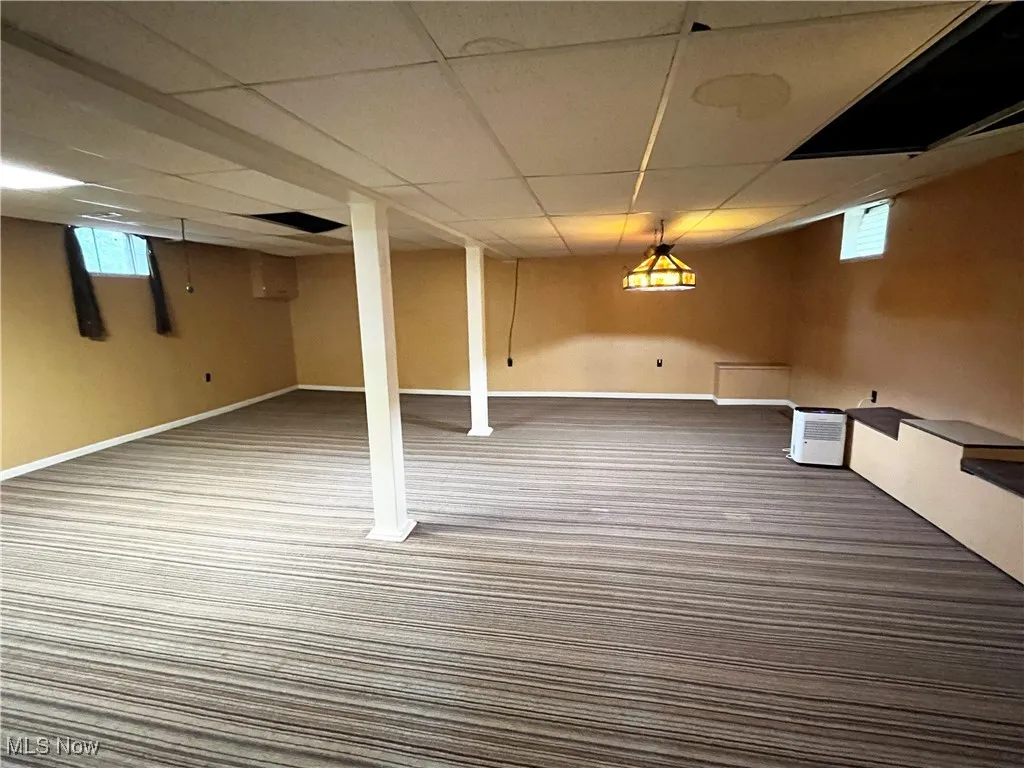 Basement featuring a paneled ceiling, plenty of natural light, and carpet floors