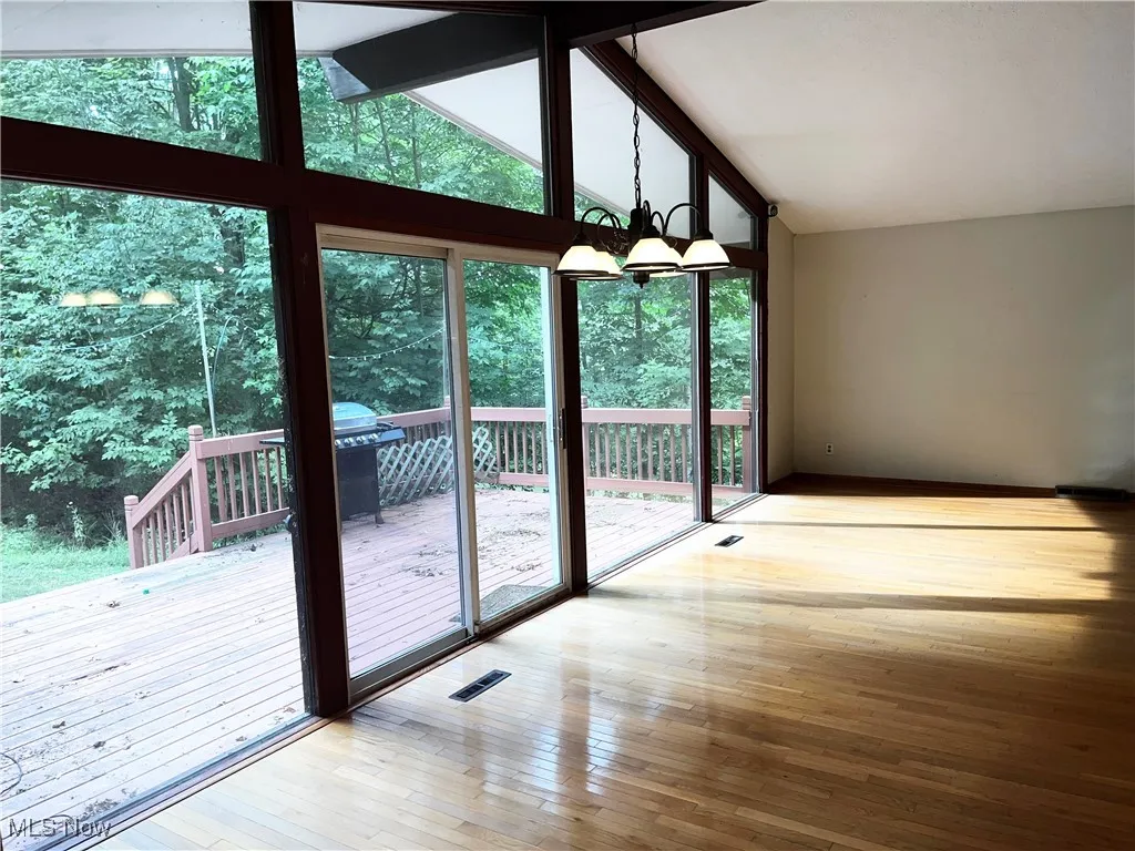 Doorway featuring a chandelier, hardwood / wood-style flooring, beam ceiling, and high vaulted ceiling