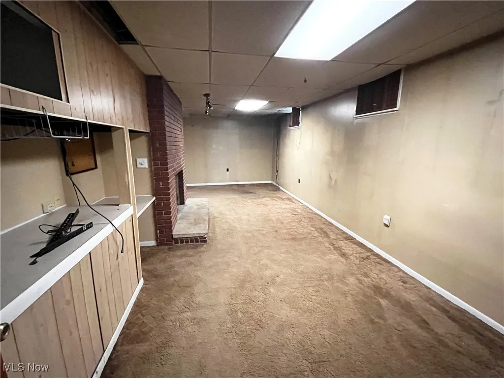 Finished below grade area with a fireplace, a paneled ceiling, and carpet floors