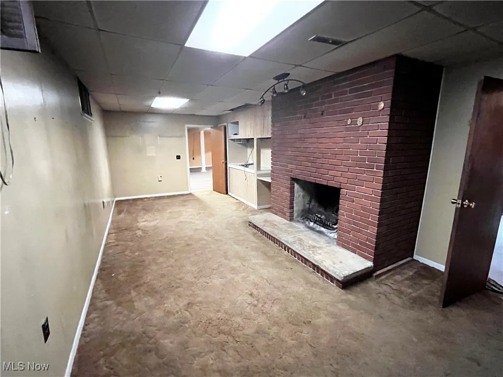 Finished below grade area featuring a paneled ceiling, light carpet, and a fireplace