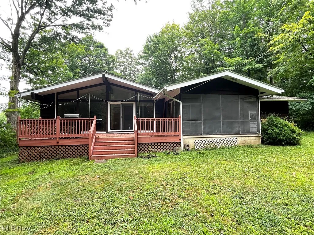 Back of property with a sunroom and a lawn