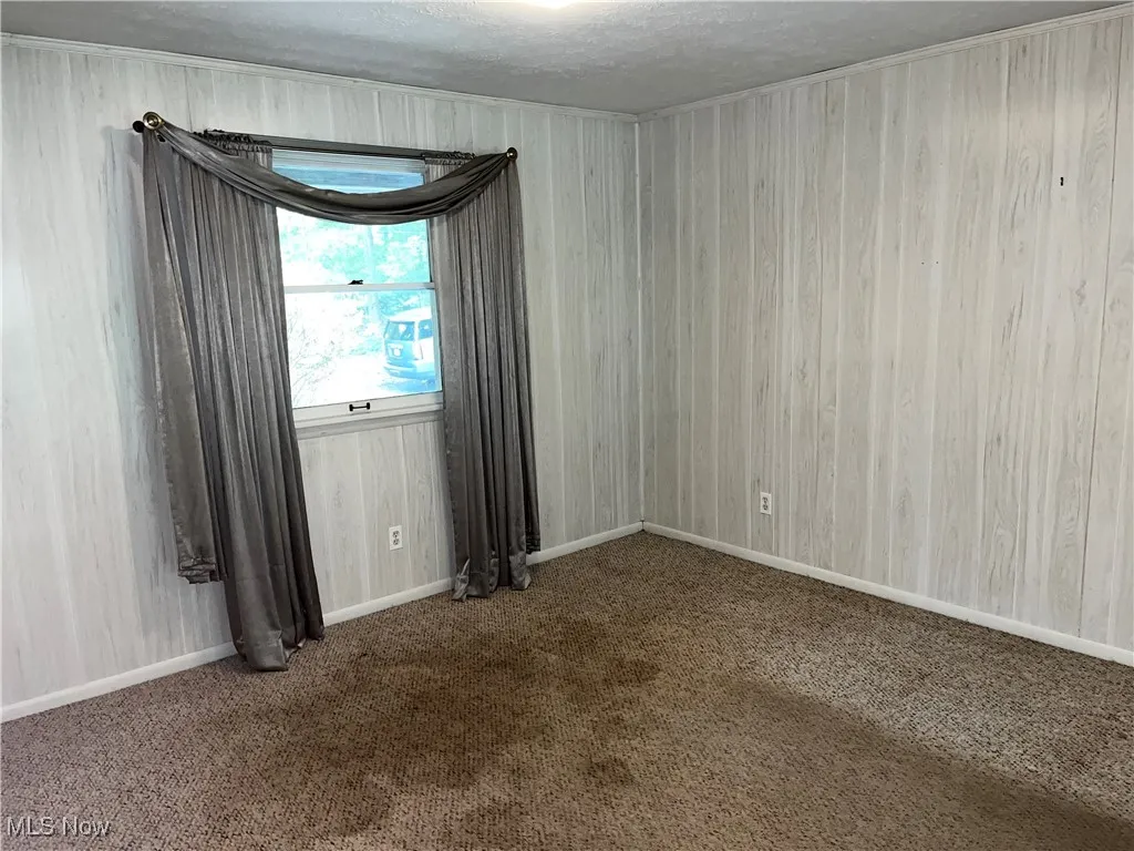Carpeted empty room featuring a textured ceiling and baseboards