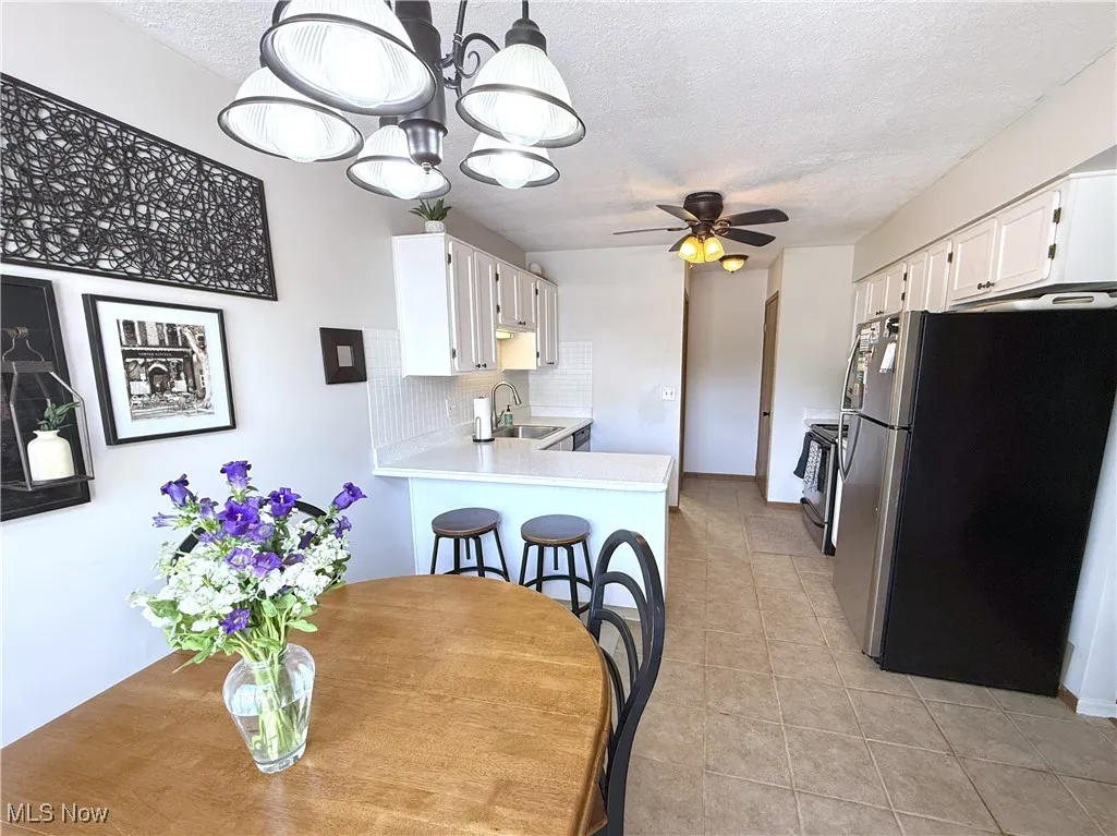 Dining space with a ceiling fan, a textured ceiling, and light tile patterned flooring