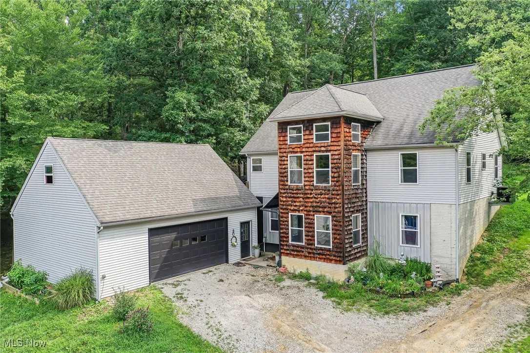 View of front of home featuring a garage, roof with shingles, an outdoor structure, and driveway