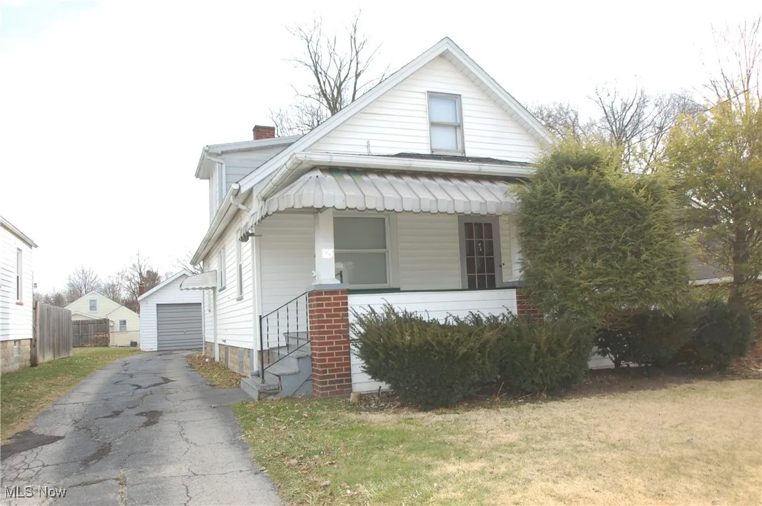 View of front of home with a chimney, an outdoor structure, a garage, and a front lawn