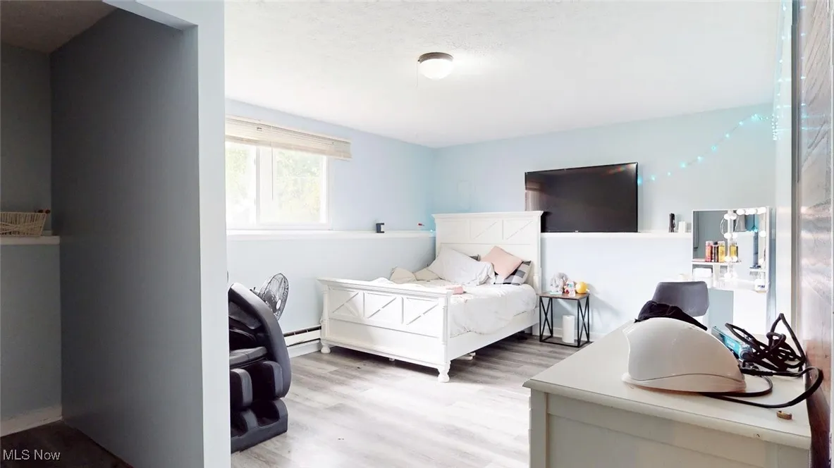 Bedroom with wood finished floors, a textured ceiling, and large closet space