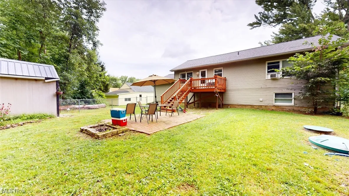 Rear view of property featuring stairway, a wooden deck, a patio, and an outdoor fire pit