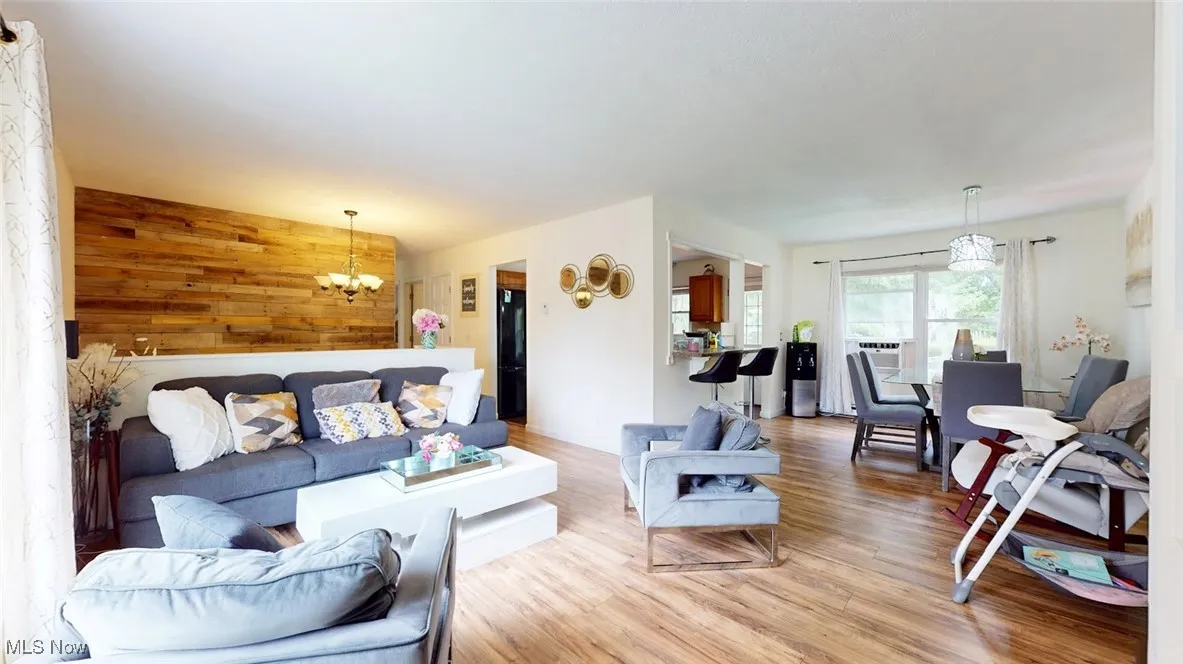 Living area with wooden walls, a chandelier, and light wood-style floors