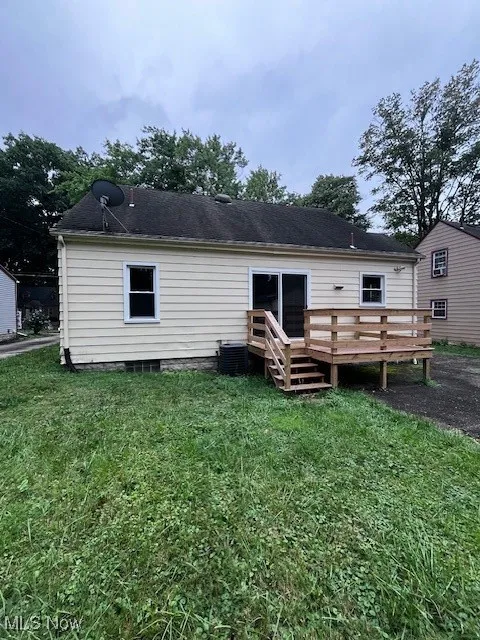 Back of property featuring a wooden deck and a yard