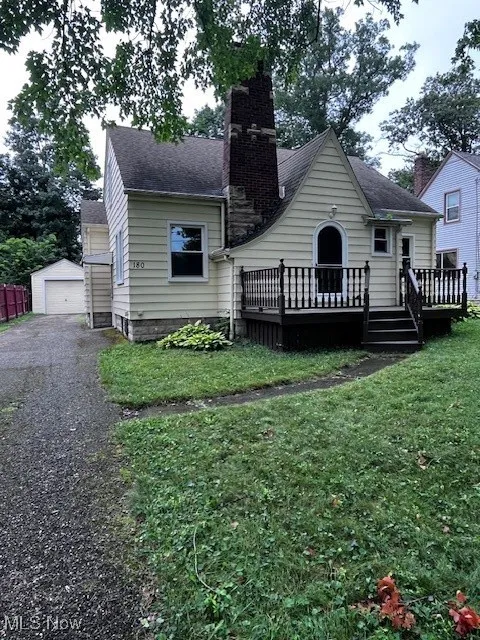 Back of house featuring a chimney, roof with shingles, a deck, and a yard