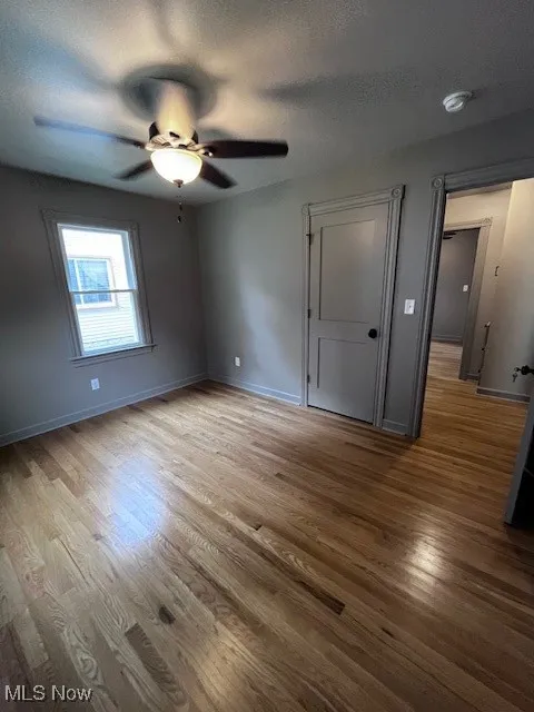 Unfurnished bedroom featuring wood finished floors, a textured ceiling, and ceiling fan