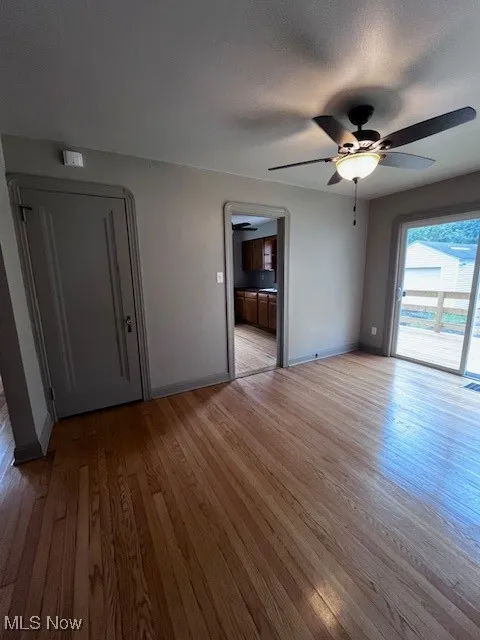 Unfurnished living room with wood finished floors, ceiling fan, and a textured ceiling