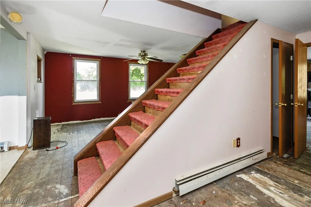 Staircase featuring baseboard heating and hardwood / wood-style floors