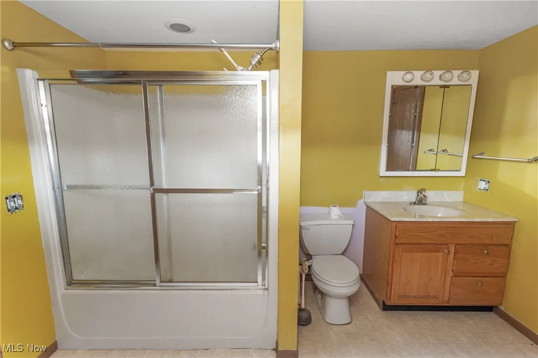 Bathroom featuring vanity, combined bath / shower with glass door, and tile patterned floors