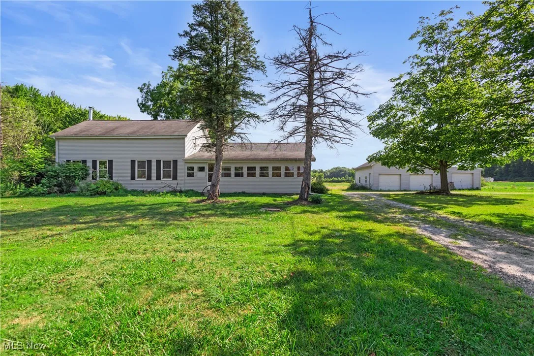 Rear view of house with a garage, a lawn, and an outbuilding