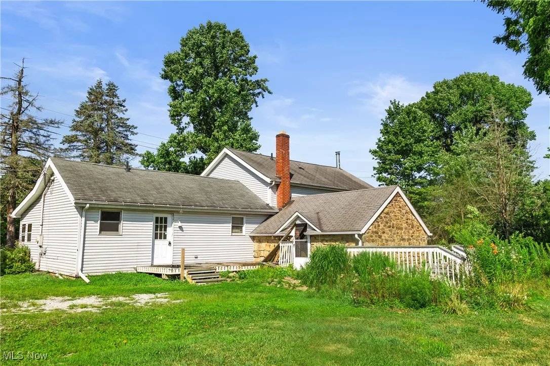 Back of house featuring a deck, a lawn, and roof with shingles