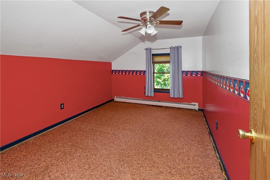 Additional living space featuring lofted ceiling, a baseboard heating unit, carpet, ceiling fan, and a textured ceiling