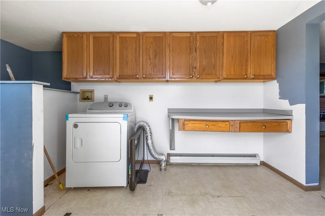 Laundry room featuring cabinet space, washer / dryer, light flooring, and baseboard heating