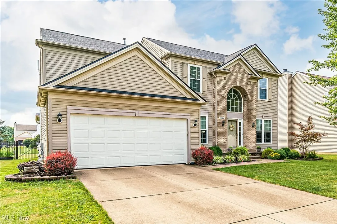 Traditional-style house with driveway, an attached garage, and brick siding