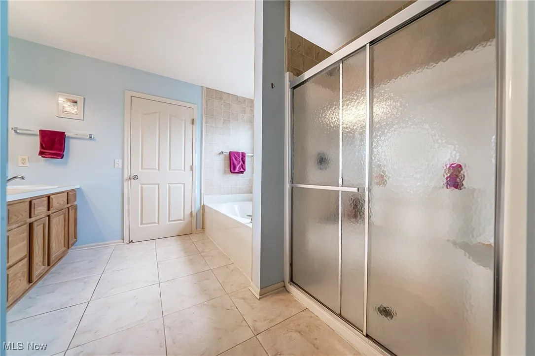 Full bath with a bath, a stall shower, vanity, and tile patterned floors