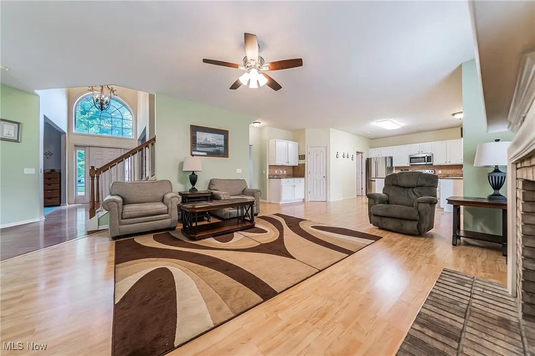 Living area with light wood-type flooring, a fireplace, a ceiling fan, and a chandelier