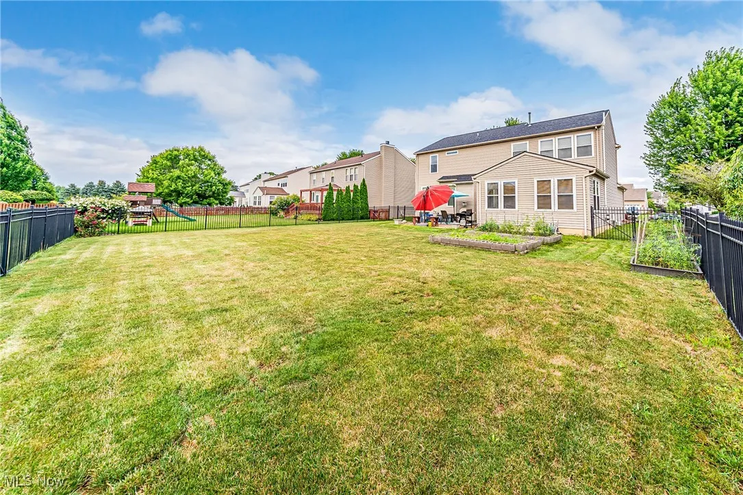 Rear view of house with a garden, a fenced backyard, and a playground