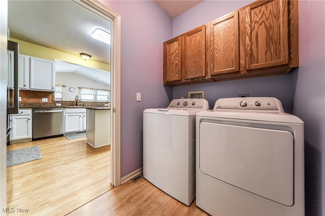 Laundry area featuring cabinet space, independent washer and dryer, and light wood finished floors