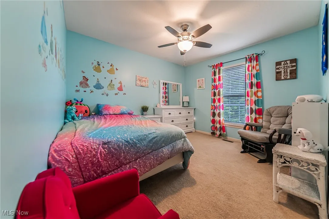 Carpeted bedroom with a ceiling fan and baseboards