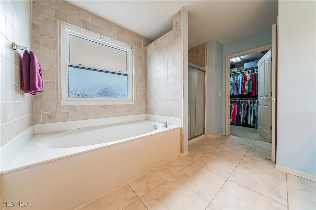 Bathroom featuring a garden tub, a stall shower, and a walk in closet