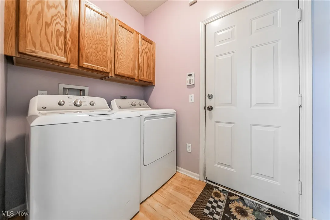 Laundry area with cabinet space, washer and clothes dryer, and light wood-style flooring