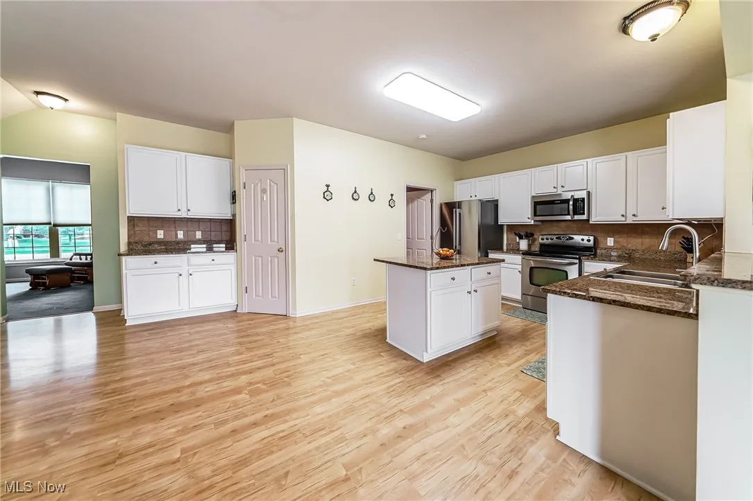 Kitchen with tasteful backsplash, appliances with stainless steel finishes, a center island, and white cabinetry