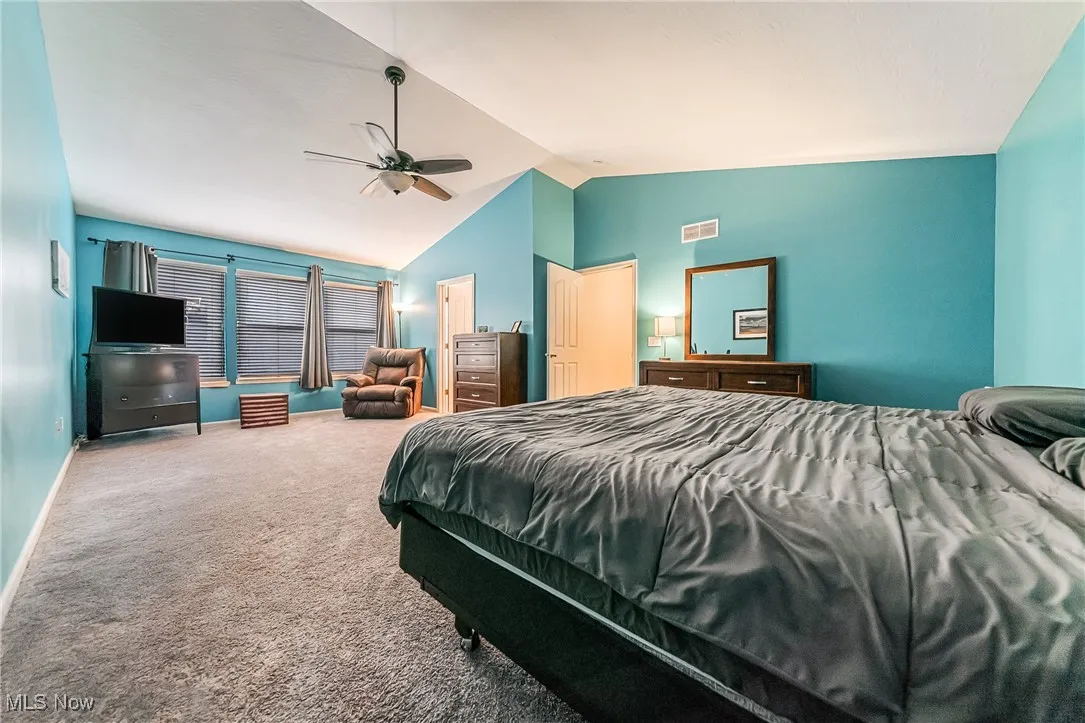 Carpeted bedroom featuring lofted ceiling and ceiling fan