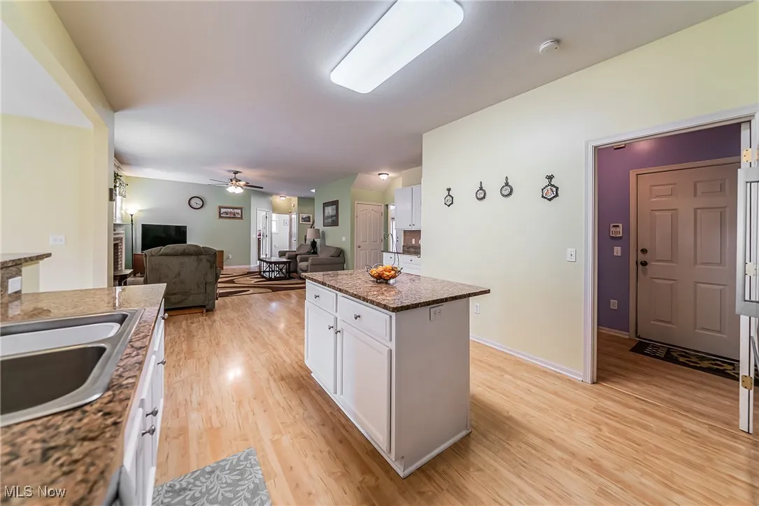 Kitchen with white cabinetry, light wood-style floors, a center island, open floor plan, and ceiling fan