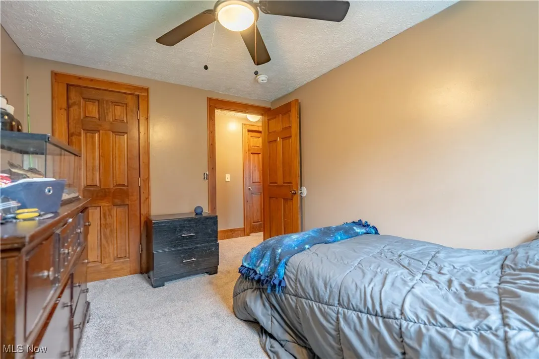 Bedroom featuring a textured ceiling, carpet floors, and a ceiling fan