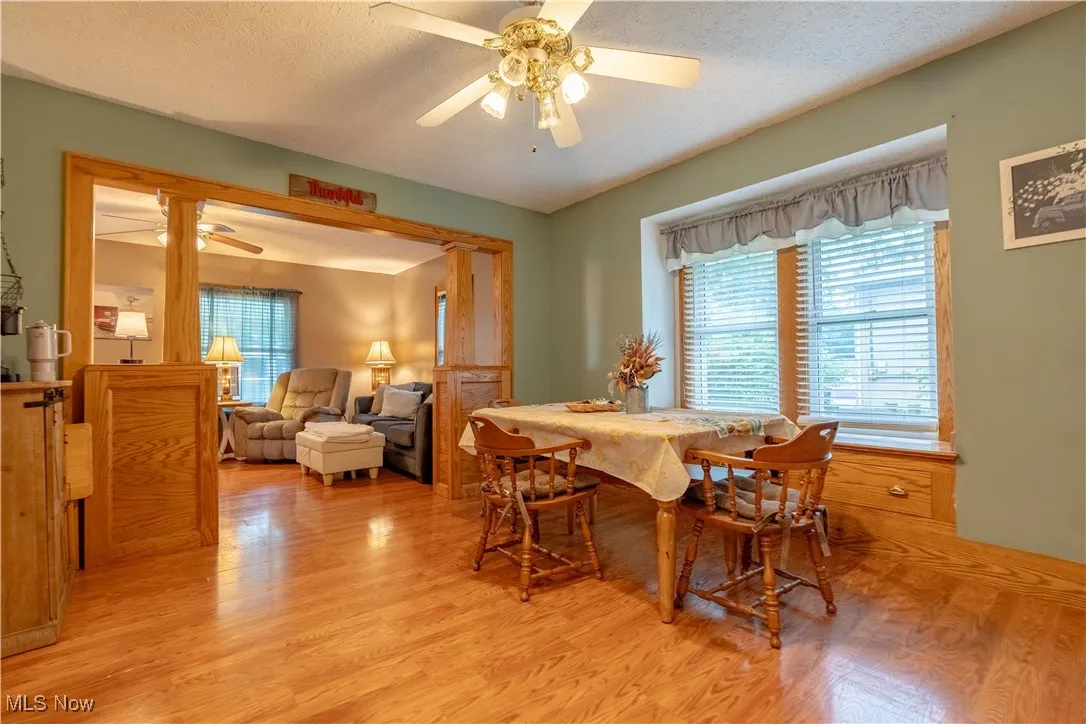 Dining area with a textured ceiling, light wood-style floors, and a ceiling fan