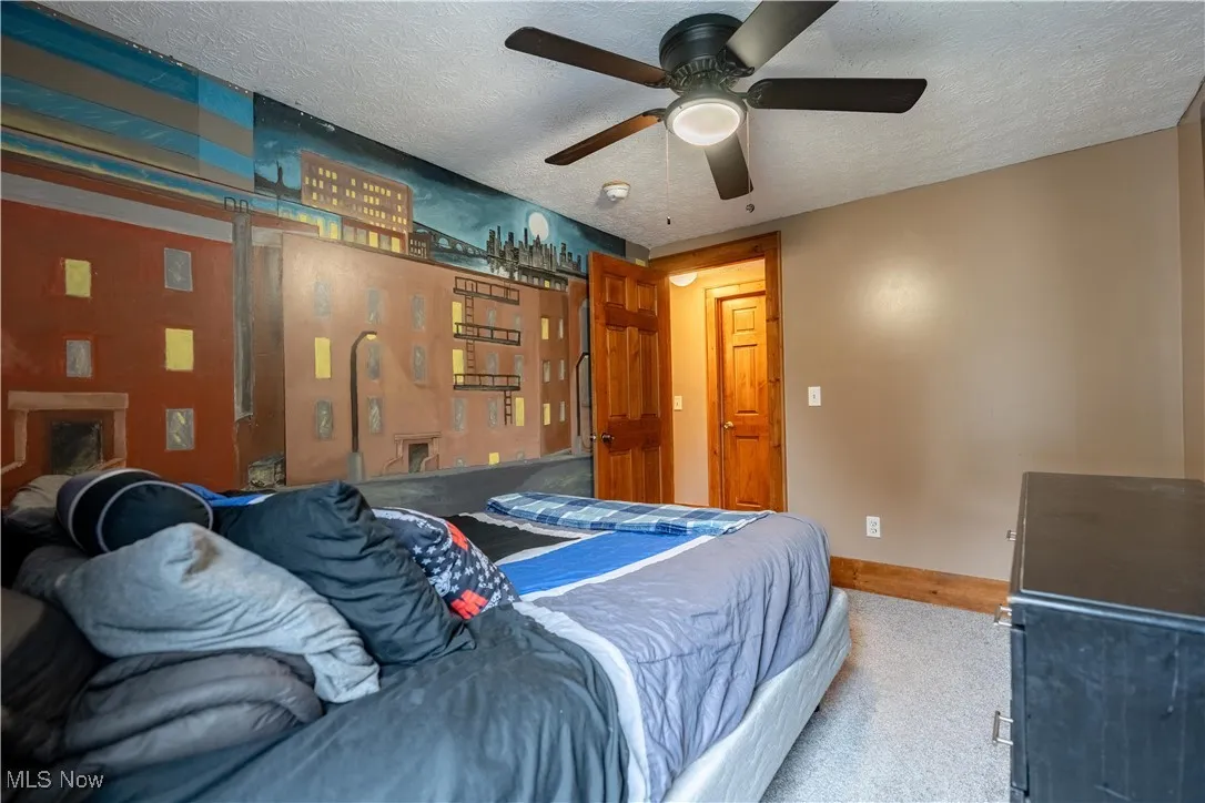 Bedroom with a textured ceiling, carpet flooring, and ceiling fan