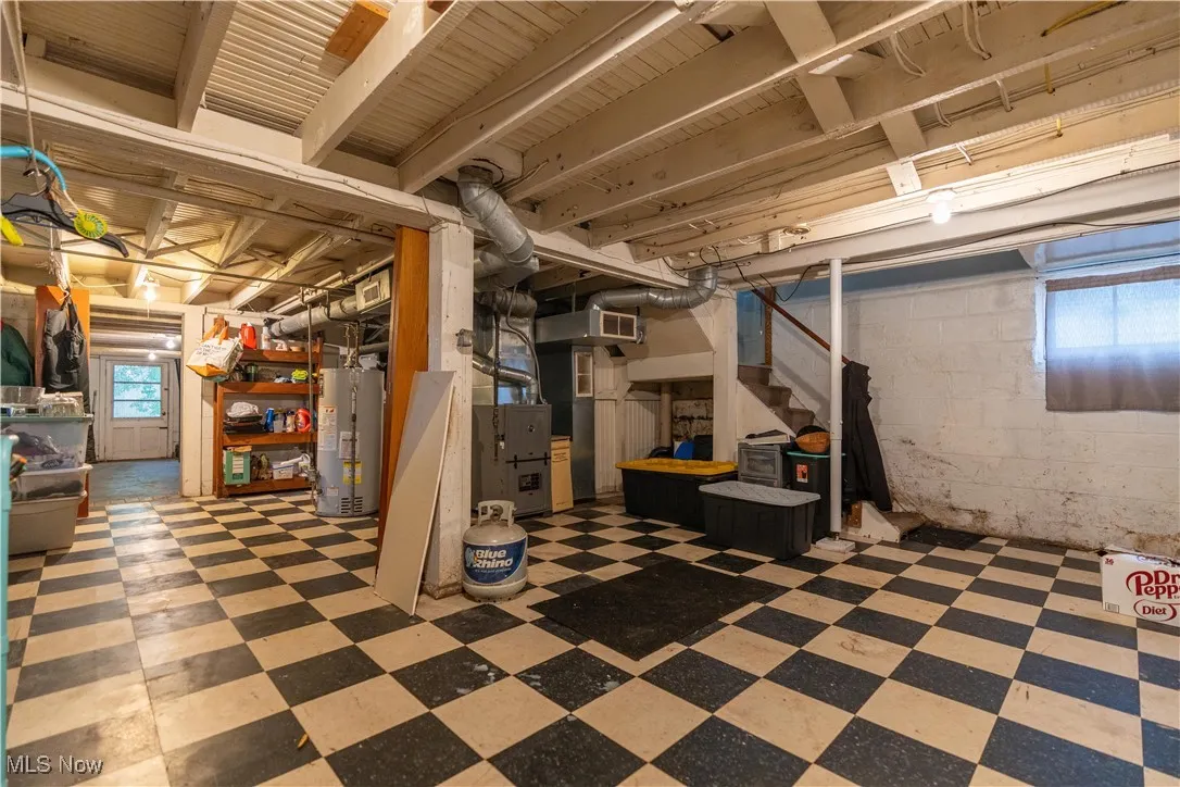 Below grade area with stairway, tile patterned floors, and gas water heater