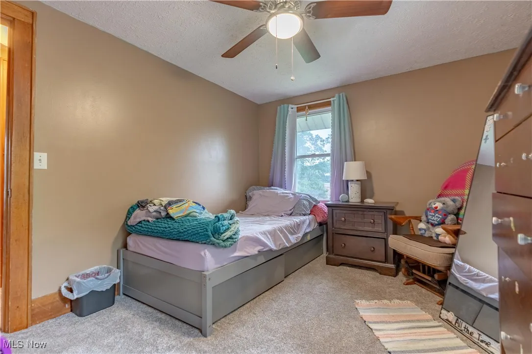 Carpeted bedroom featuring a textured ceiling and a ceiling fan