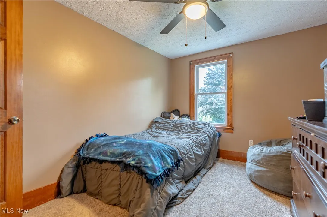 Carpeted bedroom with a textured ceiling and a ceiling fan