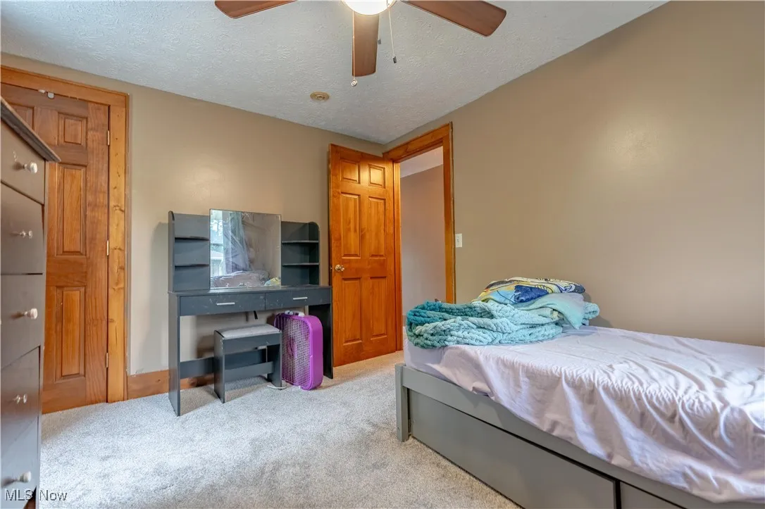 Carpeted bedroom featuring a textured ceiling and ceiling fan