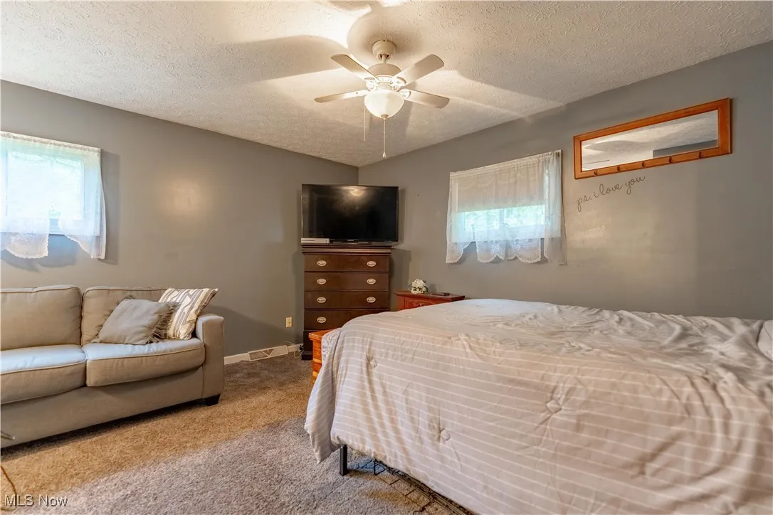 Bedroom featuring a textured ceiling, carpet, and ceiling fan
