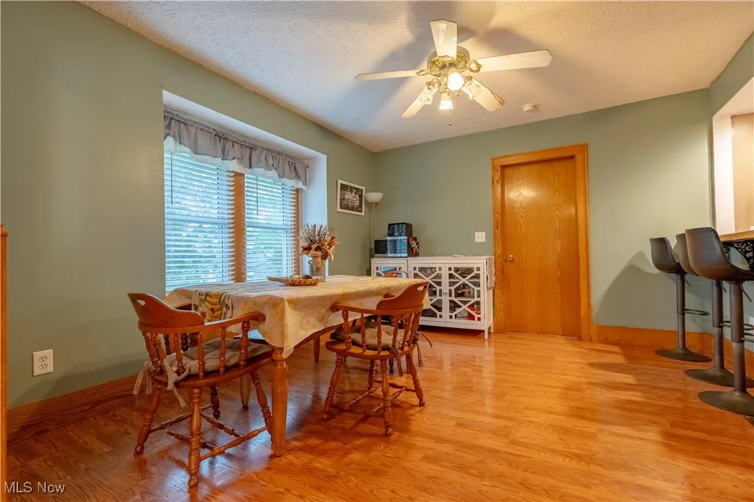 Dining space with a textured ceiling, light wood-type flooring, and ceiling fan