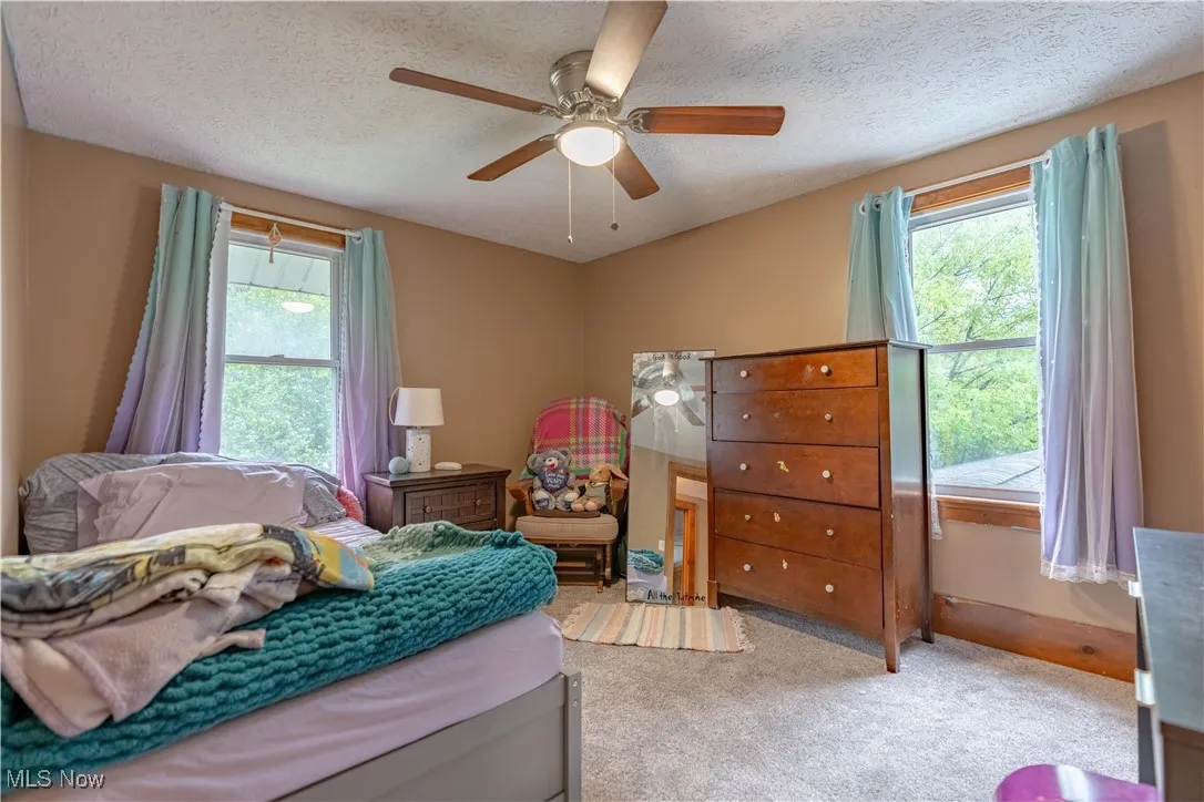 Carpeted bedroom featuring a textured ceiling and a ceiling fan
