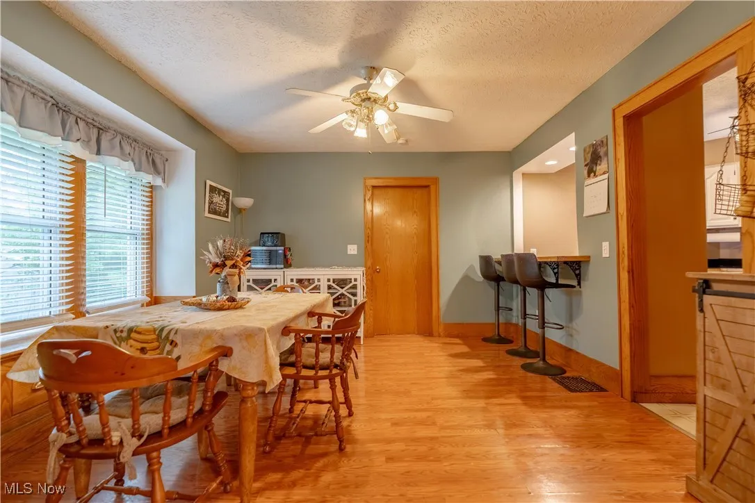 Dining area with light wood-type flooring, a textured ceiling, and ceiling fan