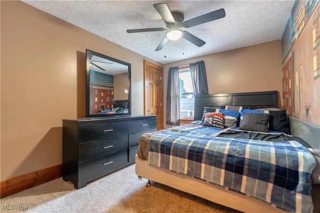 Bedroom featuring light carpet, a textured ceiling, and ceiling fan